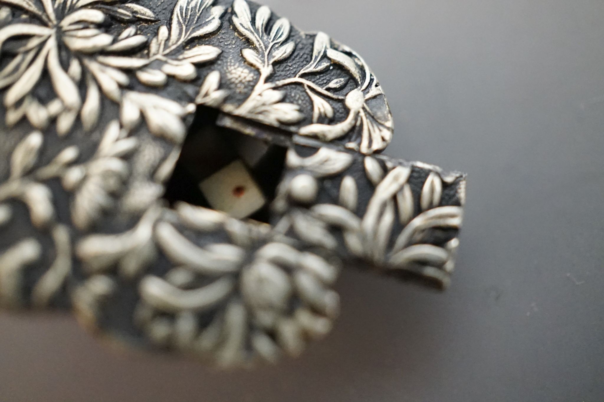 An unusual Japanese mixed metal noh mask containing minute bone dice and a stag antler noh mask brooch, signed, 3.5cm